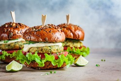 Vegan falafel burger with vegetables and sauce, dark background. Healthy food concept.