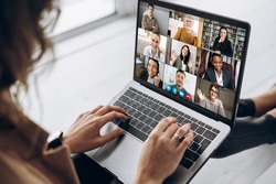 Back view of female employee communicate on video call with multiracial colleagues, woman worker conducts webcam group conference with business partners uses laptop and app