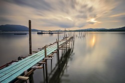 A long exposure image of empty old wooden jetty during sunset