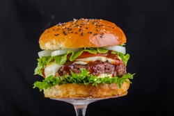 Toasted brown hamburger with mushrooms champignons, mozzarella cheese, tomato sauce, a piece of fried bacon, juicy steak from pork or beef, greens and tomato wooden chopping board, Isolated 
