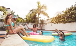 Group happy friends enjoying summer day in swimming pool with inflatable - Young multiracial people having fun in exclusive resort hotel - Youth vacation lifestyle concept 