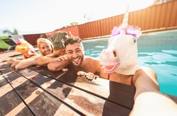 Crazy friends selfie doing pool party wearing bizarre mask - Young people having fun celebrating summer in exclusive tropical resort - Friendship and youth holidays lifestyle concept 