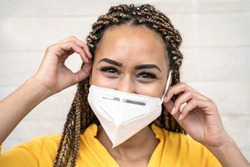 African woman with braids wearing face medical mask - Young girl using facemask for preventing and stop corona virus spread - Healthcare medical and youth millennial people concept 