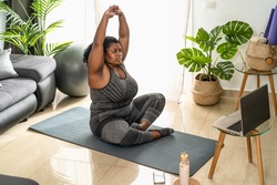 Young African curvy woman doing pilates online fitness class with laptop at home - Sport wellness people lifestyle concept