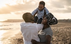 Happy African family having fun on the beach during summer holidays - Parents love concept