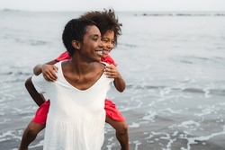 Happy African mother and daughter having fun on the beach during vacations - Lovely family lifestyle concept