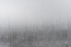 Natural drops of water flow down the glass, high humidity in room, condensation on the glass window. Neutral colors. Excellent background with condensation drops texture. Horizontal orientation 