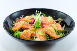 Spicy Salmon Salad with vegetable in black bowl on white background