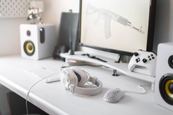 White large gaming headphones are on the table. Close-up in a bright interior