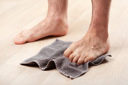 man doing flatfoot correction gymnastic exercise grabbing towel at home