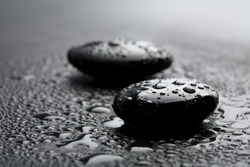 black shiny zen stones with water drops over black background