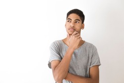 Portrait of a young African American black man thinking over an idea. Attractive thinking teenager, student. Pensive guy on a white background.   