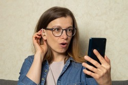 A woman using a hearing aid talks on a smartphone webcam.