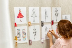 Woman fashion designer is working on creating sketches of dresses. Design and tailoring. Seamstress in the studio.