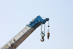 truck crane with hooks and scale weight on background is blue sky.