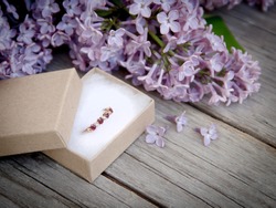 Ring in gift box and lilac on wood