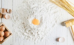 Baking background with cake ingredients on white wood from above bowl flour eggs
