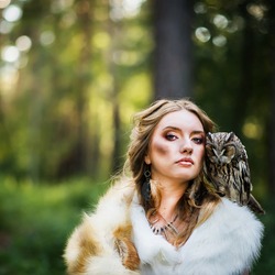 The girl is the huntress in the forest with an owl on her shoulder
