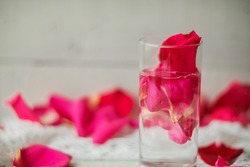 Rose pink water - water with petals of rose flowers in a transparent glass.
