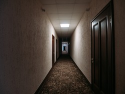Empty dark corridor in apartment building, doors, lighting lamps, perspective
