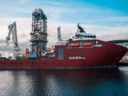 Offshore seismic vessel or ship for searching oil in port. Oil Rig and crane on background