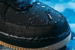 Water drops on waterproof membrane fabric of shoes surface, macro shot. New waterproofing technology for wear and footwear for active lifestyle