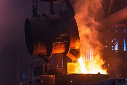 Molten metal is poured with sparks from ladle into mold. Smelting of multi-ton cast iron parts in foundry. Metallurgical plant or Steel Mill