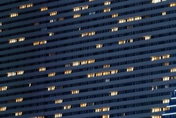 Night facade of high modern building with many illuminated windows
