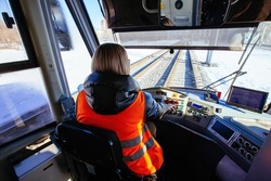 Female tram driver on workplace, view from behind.