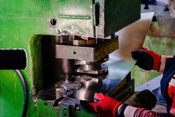 Worker operating metal press stamping machine, close up.