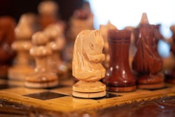 Vintage carved wooden chess pieces on a chessboard on a table indoors.