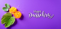 Happy Dussehra. Yellow flowers, green leaf and rice on purple pastel background. Dussehra Indian Festival concept.