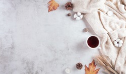 Autumn composition. A cup of coffee, cotton flowers, autumn leaves and sweater on stone background. Flat lay, top view with copy space.