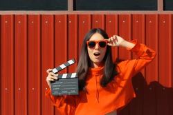 Beautiful Woman with Cinema Clapper on Red Background. Cool model girl with film slate at casting audition
