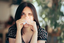Allergic Woman Blowing her Nose with a Tissue Felling Sick. Person having a congested nasal obstruction symptom from allergy season
