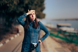 Female Tourist with Vintage Hipster Camera Forgetting Film Roll. Woman trying to remember something standing and waiting in a harbor
