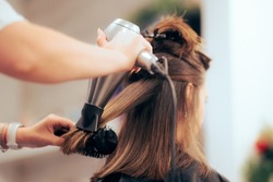 

Woman Having her Hair Straighten with a Brush and a Hair Dryer. Hairdresser drying clients hair working with professional tools
