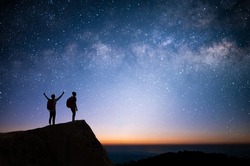 Silhouette of two young man standing, open arms and watched the star, milky way and night sky on top of the mountain. They enjoyed traveling and was successful when he reached the summit.