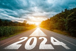 New year 2024 or straight forward concept. Text 2024 written on the road in the middle of asphalt road with at sunset. Concept of planning, goal, challenge, new year resolution.
