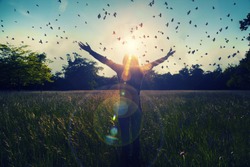 Young girl spreading hands with joy and inspiration facing the sun,sun greeting,freedom concept,bird flying above sign of freedom and liberty 