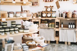 Zero waste shop interior details. Wooden shelves with different food goods and personal hygiene or cosmetics products in plastic free grocery store. Eco-friendly shopping at local small businesses
