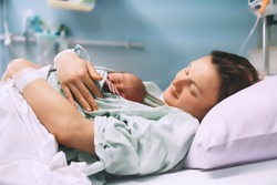 Mother and newborn. Child birth in maternity hospital. Young mom hugging her newborn baby after delivery. Woman giving birth. First moments of baby life after labor.