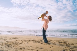 Mother with small child playing and having fun together on beach ocean. Happy family outdoors. Mom and baby at summer on nature. Positive human emotions and feelings. Family holiday on sea coast.
