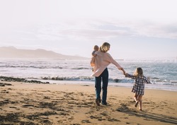 Mother with children playing and having fun together on beach ocean. Happy family outdoors. Mom and kids at summer on nature. Positive human emotions and feelings. Family holiday on sea coast.