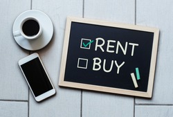 Rent not Buy blackboard concept. Choosing renting over buying with coffee and mobile phone