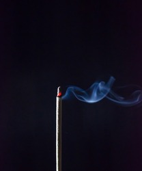 Incense stick are burning on the black background. The smoke of incense