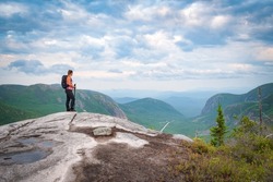 A lone woman hiking Charlevoix mountains, looking down in the valley, taking rest at the summit, QC, Canada