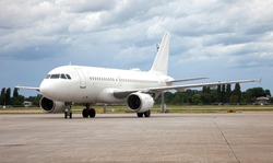 Passanger white plane lands. Airplane on the platform of Airport. Runway. Landing aircraft closeup. Mockup plane with place for text. Cloudy sky. Copy space. Cloudy sky.
