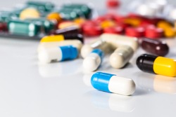 Antibiotics contain blue pills, yellow-red or capsules on a white background with copied clearance. Medication in healthy containers, antibiotics and dangerous drugs.