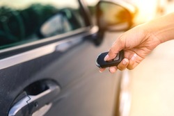 A focus image of a businesswoman's hand pressing a close-up car key in the evening after work